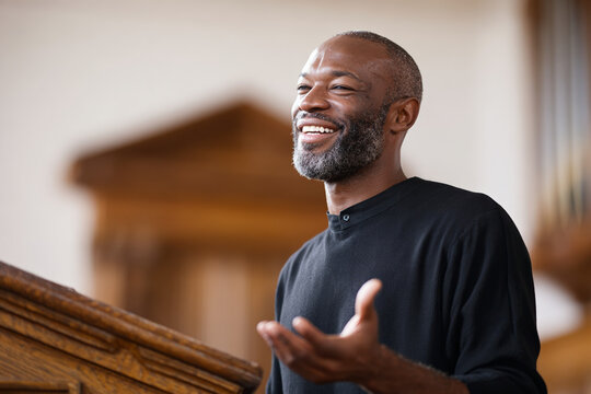 Man smiling and speaking at wooden lectern in interior