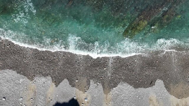 Top down view of the waves at the beach. Right to left side camera movement