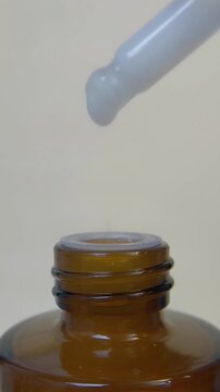 Closed up view of a dropper dripping a milky white liquid into the bottle.