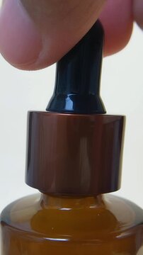 Process of opening bottle cap of product packaging containing white milky liquid. Front view vertical close up. Skincare or cosmetic texture concept.