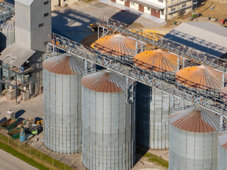 Drones capture aerial view of grain silos in an industrial area during bright daylight with visible structures. © 24K-Production