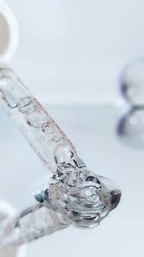 Closeup serum pipette clear bubbly liquid on glass reflection beauty skincare macro