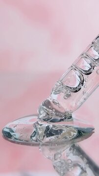 Transparent pipette with clear serum liquid bubbles soft pink background closeup side view