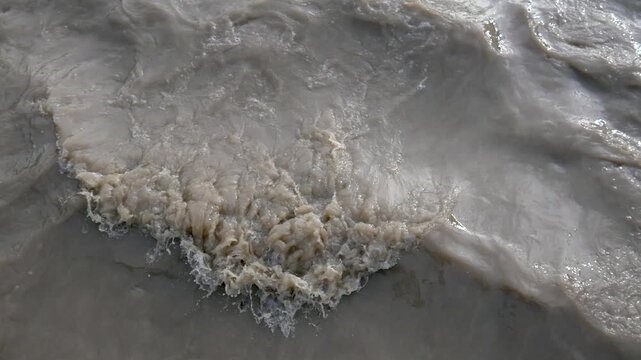 Top Down View of Muddy Flood Water Flowing Fast with Foam During Monsoon Season