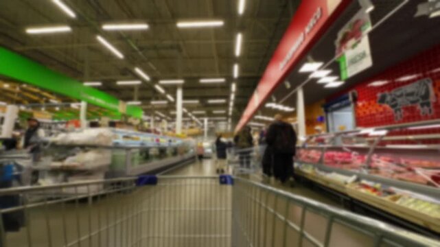 Interior of a supermarket aisle captured in a blurred style, showing shelves filled with various products on both sides.
