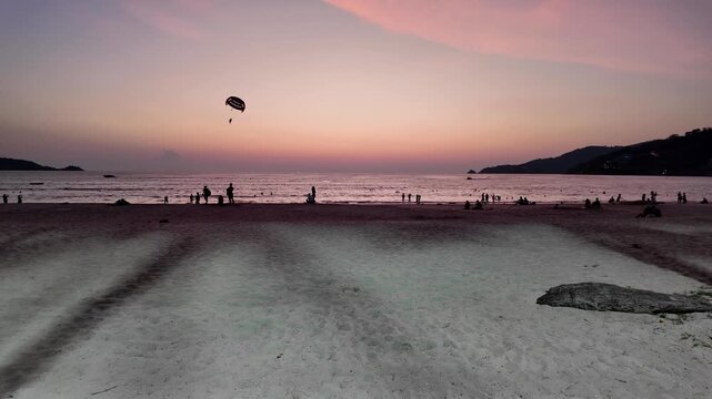 Tropical Beach Sunset with Parasailing Silhouette and Ocean Horizon in Thailand