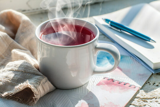 Glossy white ceramic mug overflowing with hot‑pink hibiscus tea, sun‑kissed summer flat lay, high‑saturation commercial style