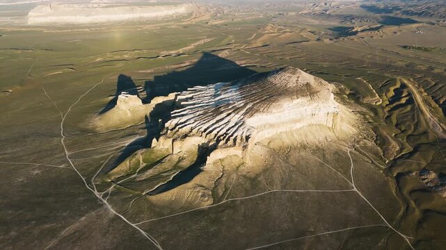 Drone footage of the famous landmark Mount Sherkala with its unique shape. Summer day, greening grass around the rock formation amidst the arid desert zone of Mangystau. geology of Kazakhstan