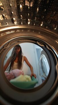 Woman arranges towels. Woman carefully places towels inside washer
