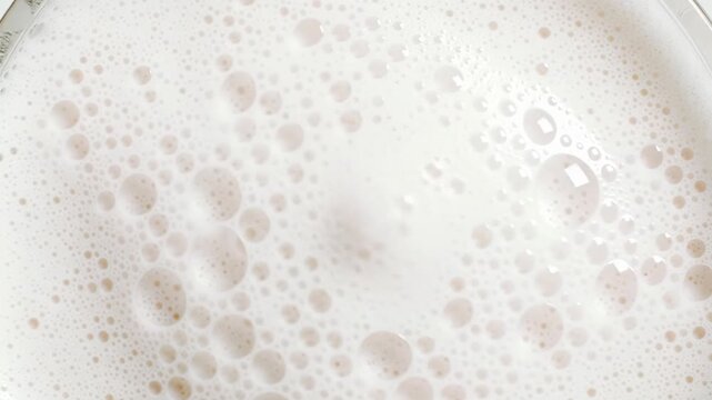 Extreme close-up of pristine, pearly white milk foam, delicate latte froth with bubbles slowly popping, forming abstract, ephemeral patterns, concept of perfection nature and microcosm