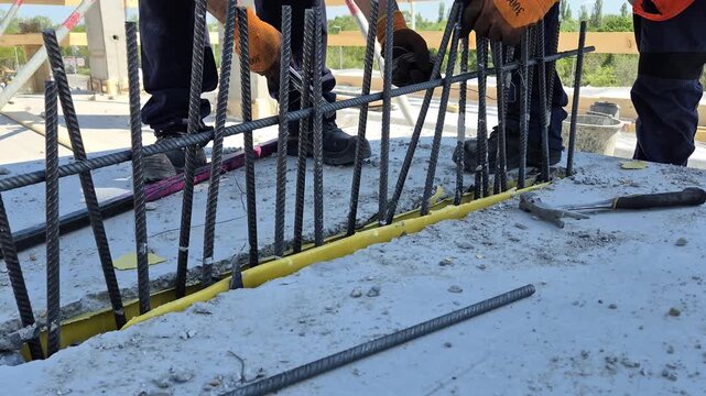 Construction worker assembling steel rebar loops and reinforcement bars between precast concrete walls before concreting, slow motion.