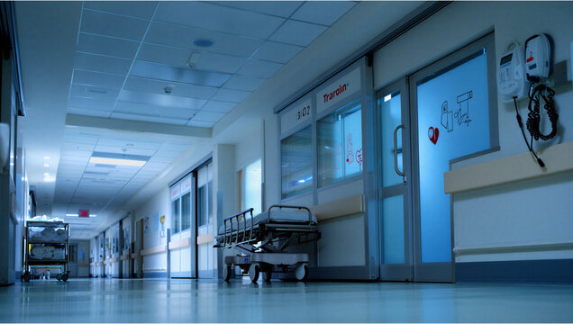 Dimly lit empty hospital hallway at night with hospital corridor, medical equipm