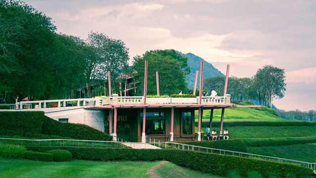 Contemporary building with deck and green landscape under cloudy sky, building