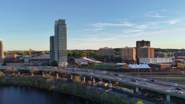 Panoramic aerial view of the BU Bridge and Charles River at golden hour, featuring highway traffic on I-90 and the distant Boston city skyline.