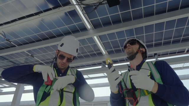 Engineers maintenance solar panels rooftop green energy technician inspection and wiring test under photovoltaic array structure with gloves helmets tools teamwork safety for reliable power output
