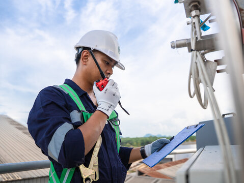 Environmental engineer communicating with team of technicians use radio and taking reports checking continuous emission monitoring systems at industrial plant. Sustainable air pollution reduction. ESG