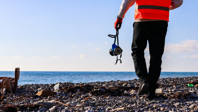 Person in vest walking with litter picker on beach