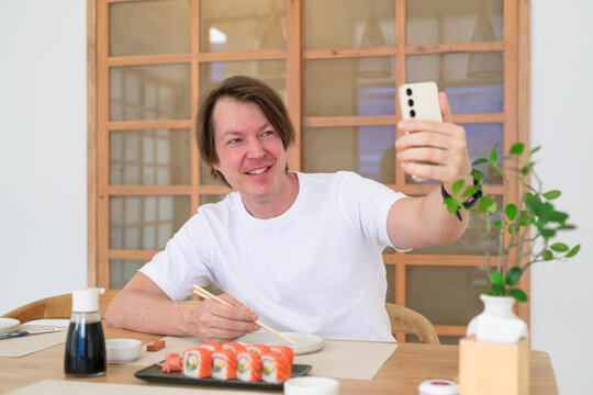 Smiling Scandinavian man taking a selfie with sushi at a restaurant