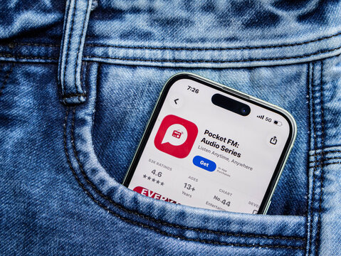Smartphone showing the pocket fm app store page inside a blue denim jeans pocket