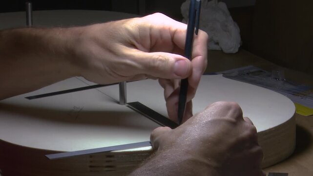 Bilbao, spain; may 21 2022: luthier drawing lines on an acoustic guitar soundboard