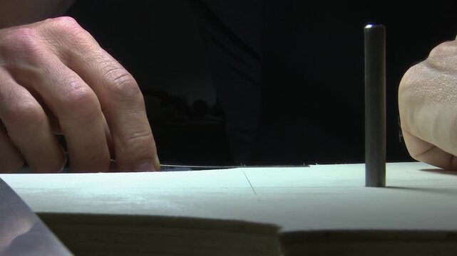 Bilbao, spain; may 21 2022: luthier using a rasp to shape the soundboard of a cello