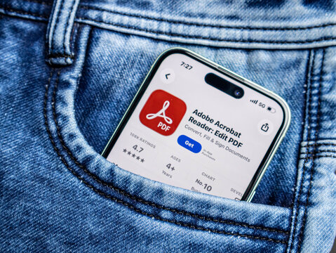 Smartphone with adobe acrobat reader app store page in a blue denim jeans pocket
