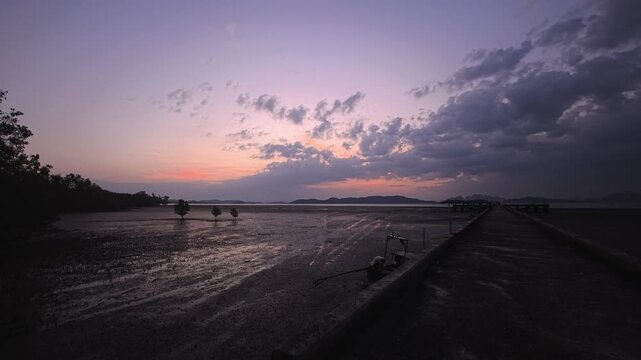 Purple dusk over tidal flats with pier and distant island silhouettes