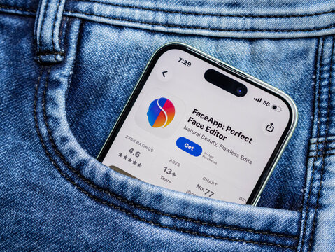Smartphone in a blue denim jeans pocket displaying the faceapp application page on the app store screen