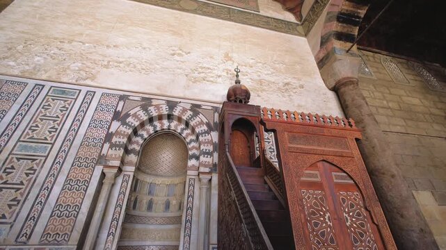 Slow motion upward camera movement revealing ornate mihrab and carved wooden minbar inside historic mosque in Cairo, Egypt. Beautiful Islamic architecture and geometric details captured in cinematic 4