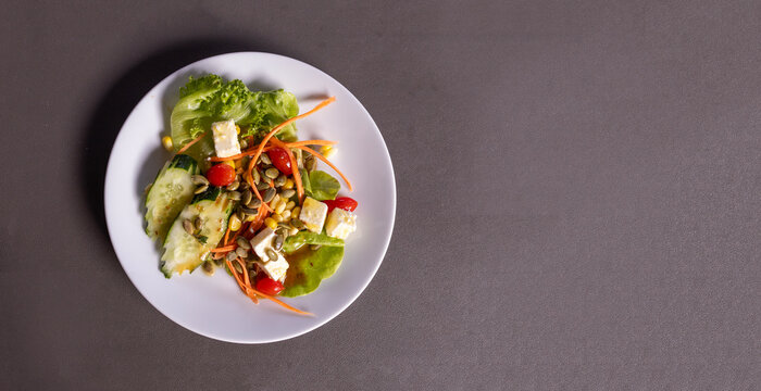 Delicious Plate of Healthy Salad with Lettuce, Carrots, Cucumbers, Tomatoes, Peppers, Feta and Sunflower Seeds with Space for Copy