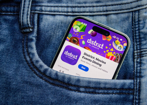 A smartphone showing the district by zomato app store page, placed inside the pocket of blue denim jeans, representing modern lifestyle and technology