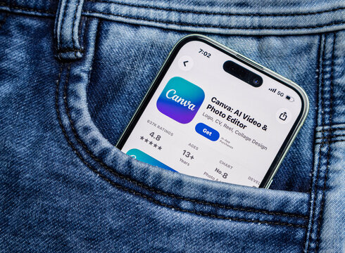 Smartphone with canva app store page displayed inside a blue denim jeans pocket