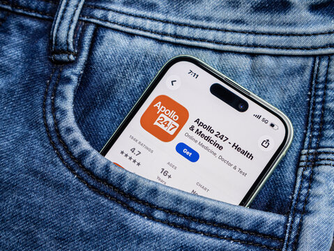 A smartphone displaying the apollo 247 health and medicine app store page, tucked inside a blue denim jeans pocket