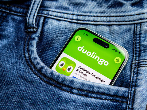 Smartphone with duolingo app icon on screen inside a blue denim jeans pocket