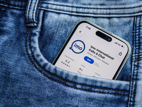 Smartphone in a blue denim jeans pocket displaying the imo international calls and chat application page on the app store
