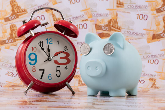 A piggy bank with one ruble coins instead of eyes against a background of 100 ruble coins