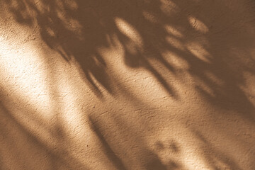Dappled sunlight through leaves creates a soft pattern on an ochre plaster wall. Warm Mediterranean aesthetic, abstract nature background, tranquil atmosphere, summer travel vibes concept © magic_cinema
