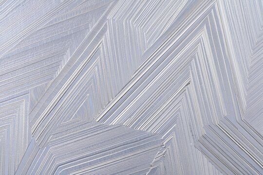 Abstract geometric pattern forming textured shapes with parallel lines and metallic gray and white colors
