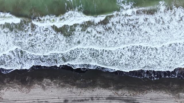 Waves roll onto the beach, creating foam as they reach the shore. The water meets the sand, forming a clear boundary between land and sea.