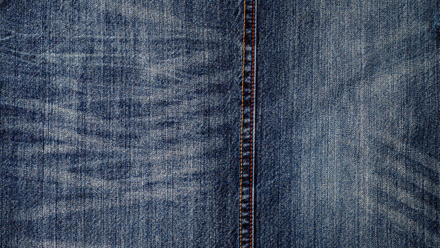 Denim fabric with visible patterns and stitching seen on a flat surface in natural light during daytime