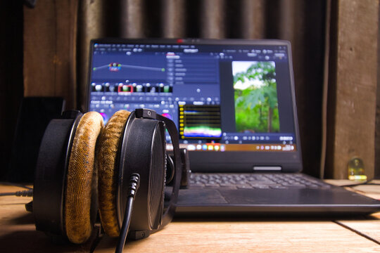 Creative video editor workspace with headphones and editing software on a laptop.