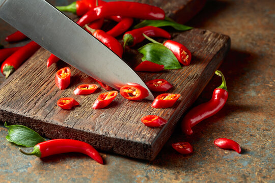Kitchen knife and ​​​​wedges of red hot chili peppers.