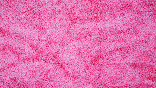 Soft pink fabric lies flat on a surface, showcasing a fuzzy texture with different patterns and designs, inviting touch and warmth