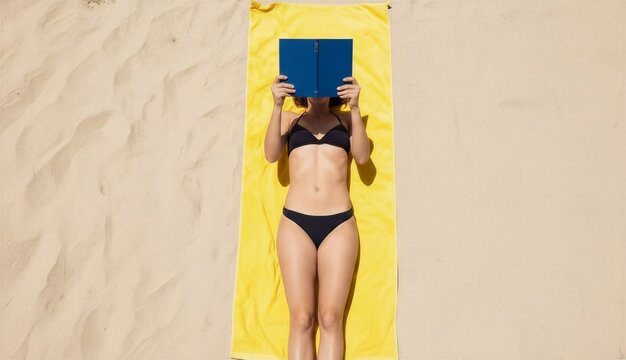 Young woman relaxing on beach towel while reading a book  