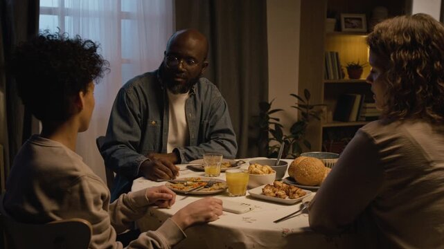 Family conflict scene with strict parents scolding son for bad behavior at dinner table, teenage boy listening and talking back