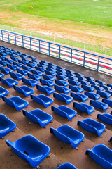 Naklejka premium Perspective rows of bright blue spectator chairs with green field background.