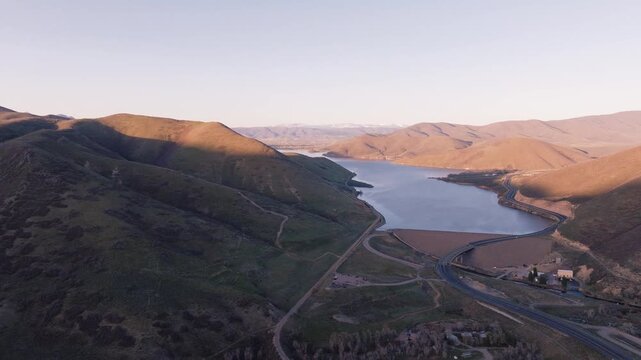 Aerial view of Provo Canyon featuring the reservoir and dam surrounded by rolling hills and winding roads during golden hour in Orem, Utah, United States.