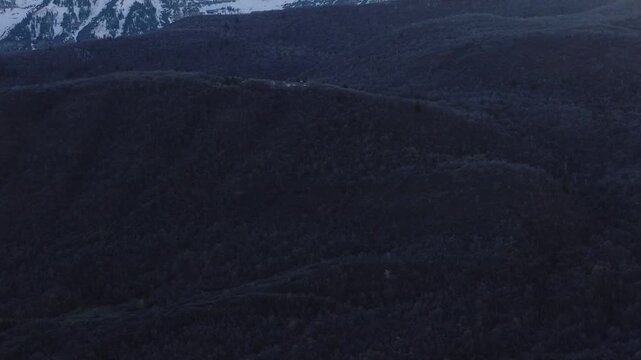 Aerial view of Provo Canyon with dense forest slopes and snow-capped mountain peaks during twilight in Orem, Utah, United States.