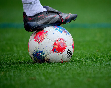 A football boot rests on a Bundesliga match ball on the pitch before kick-off.