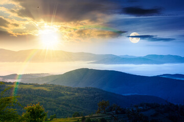 Obraz premium day meet night. foggy carpathian countryside on summer solstice. view of mountainous landscape with rural fields on rolling hills. sun and moon over fog in the valley. clouds above the mountain